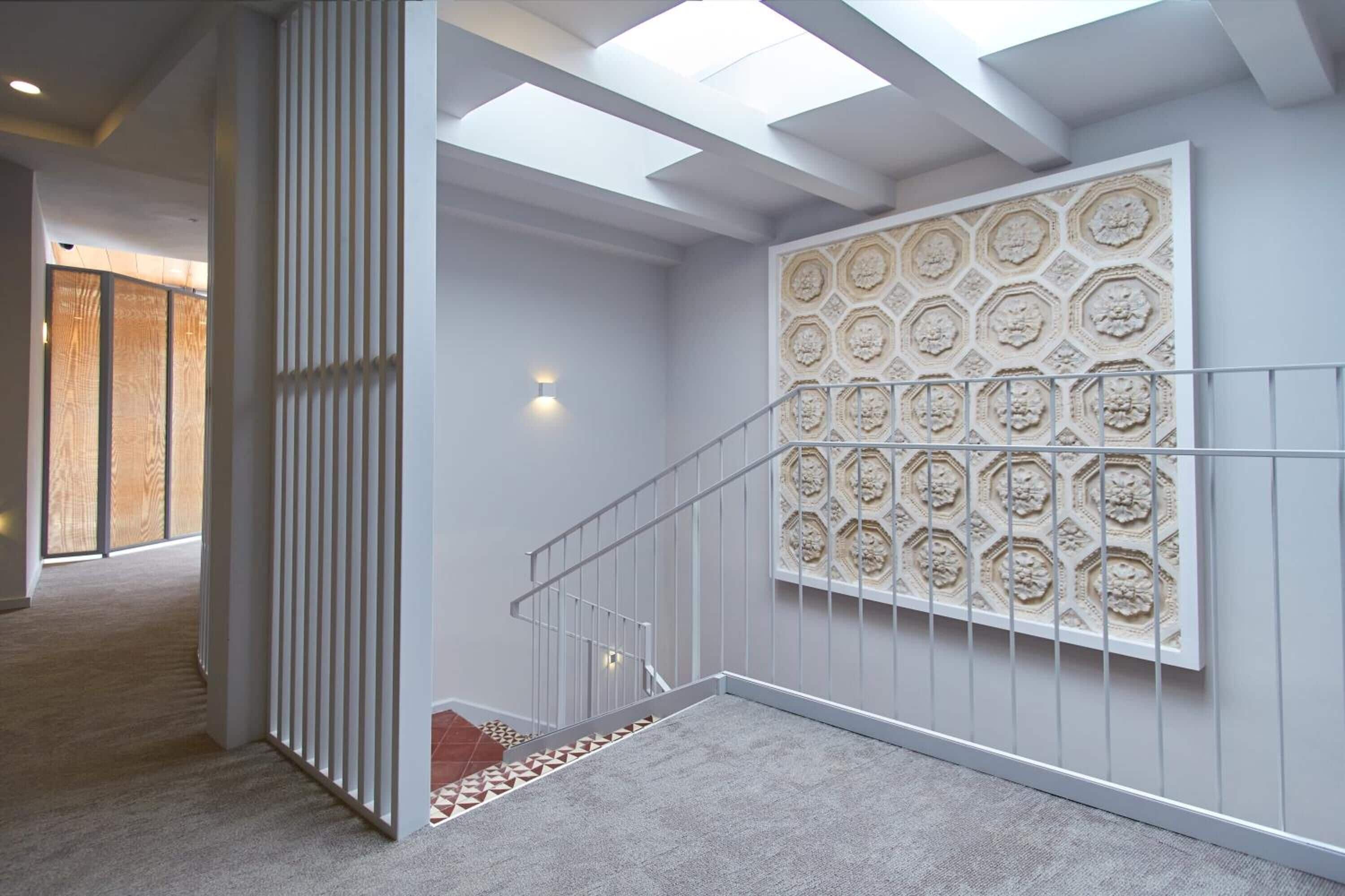 Una escalera con un papel tapiz decorado y una lámpara.
