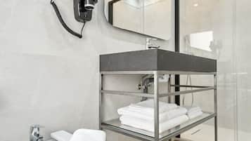 Een moderne badkamer met een douchecabine van glas, een metalen wastafelmeubel en een handdoekhouder.