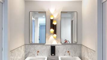 Un baño moderno con dos lavamanos, encimeras de mármol y un suelo con estampado geométrico.