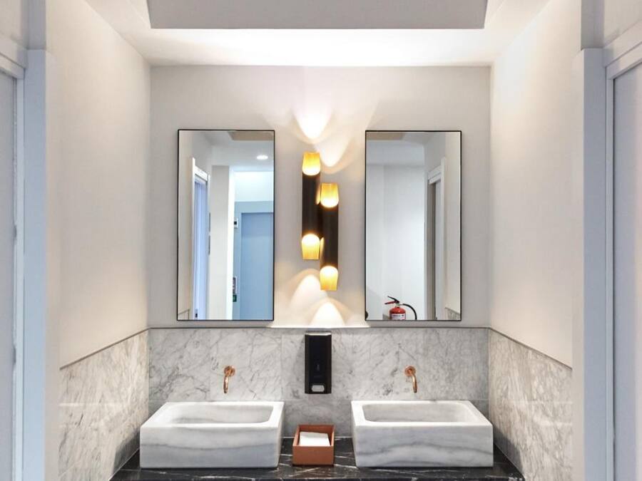 Un baño moderno con dos lavamanos, encimeras de mármol y un suelo con estampado geométrico.