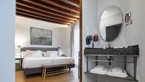 Een moderne slaapkamer met een bed, nachtkastje en een spiegel aan de muur.