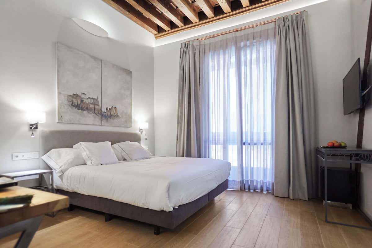 Une chambre d’hôtel moderne, dotée d’un grand lit, d’une télévision à écran plat, d’un bureau et d’un tableau au mur.