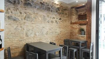 A dining area with a stone wall, wooden beams, and a patterned floor.