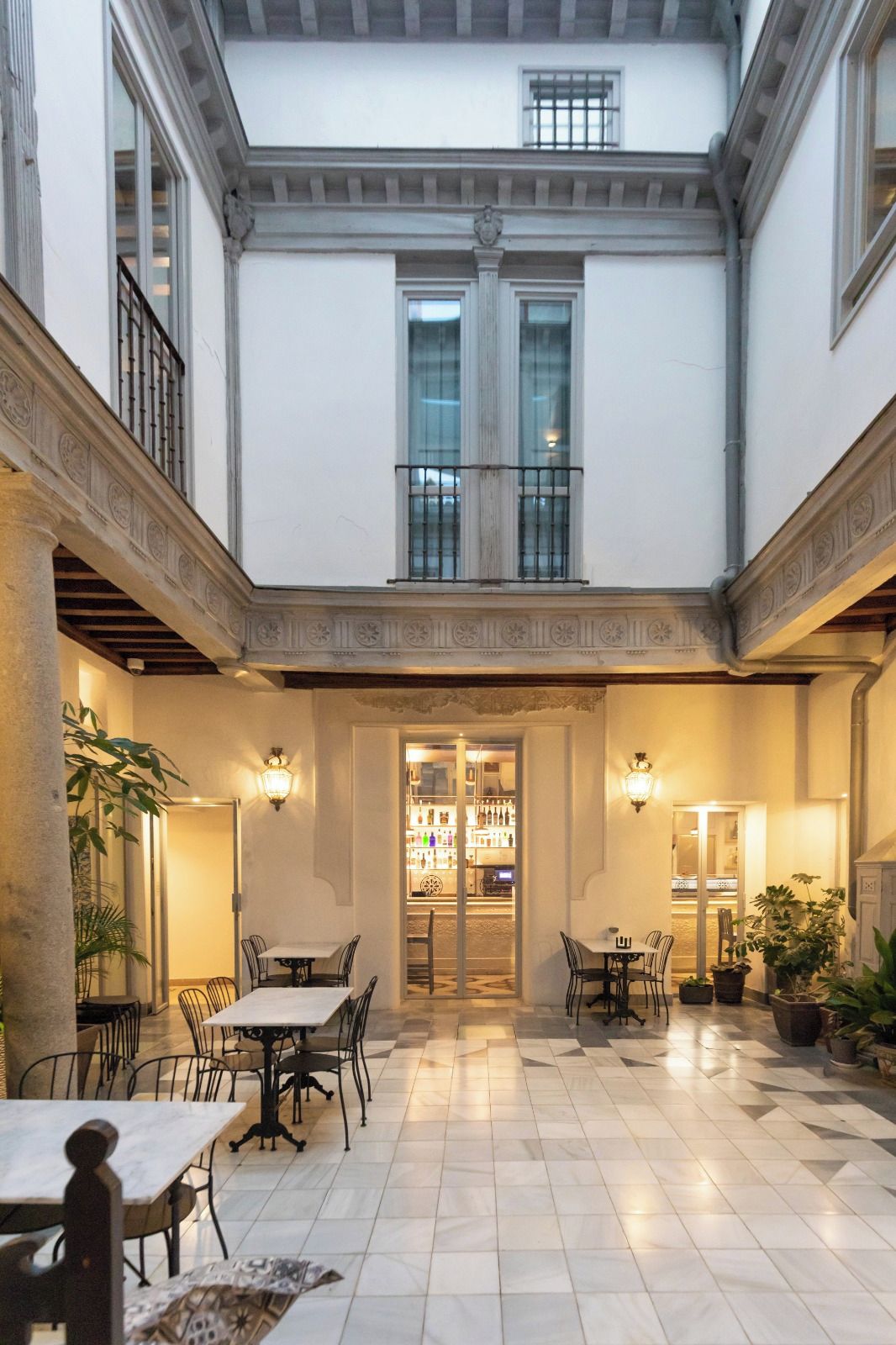 A courtyard with a bar area, multiple seating arrangements, and a tiled floor.