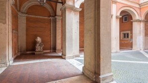 Ein Innenhof mit Säulen, einer Statue und einem gefliesten Boden.