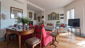Ein Wohnzimmer mit Esstisch, rotem Sofa und Fernseher.