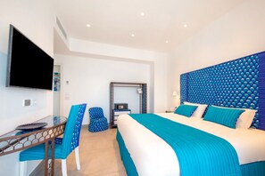 A modern hotel room with a large bed, a TV, a desk with a chair, and a mirror. - My Exclusive Italy - Beachfront Villa Sorrento & private sea access (Sorrento)