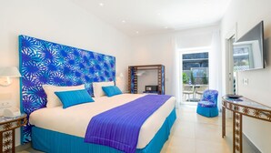 A hotel room with a large bed, a TV, a balcony with outdoor furniture, and a patterned headboard. - My Exclusive Italy - Beachfront Villa Sorrento & private sea access (Sorrento)