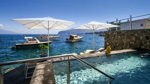 A clear blue sea with boats, a stone wall, and umbrellas. - My Exclusive Italy - Beachfront Villa Sorrento & private sea access (Sorrento)