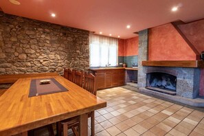 Une cuisine avec un mur en pierre, une table à manger en bois et une cheminée.
