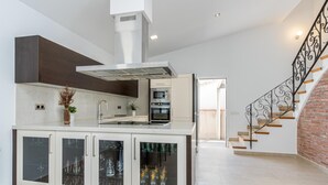 A modern kitchen with a central island, built-in oven, and a stainless steel range hood. - New house with private heated pool, parking, wifi, games room (Empuriabrava)