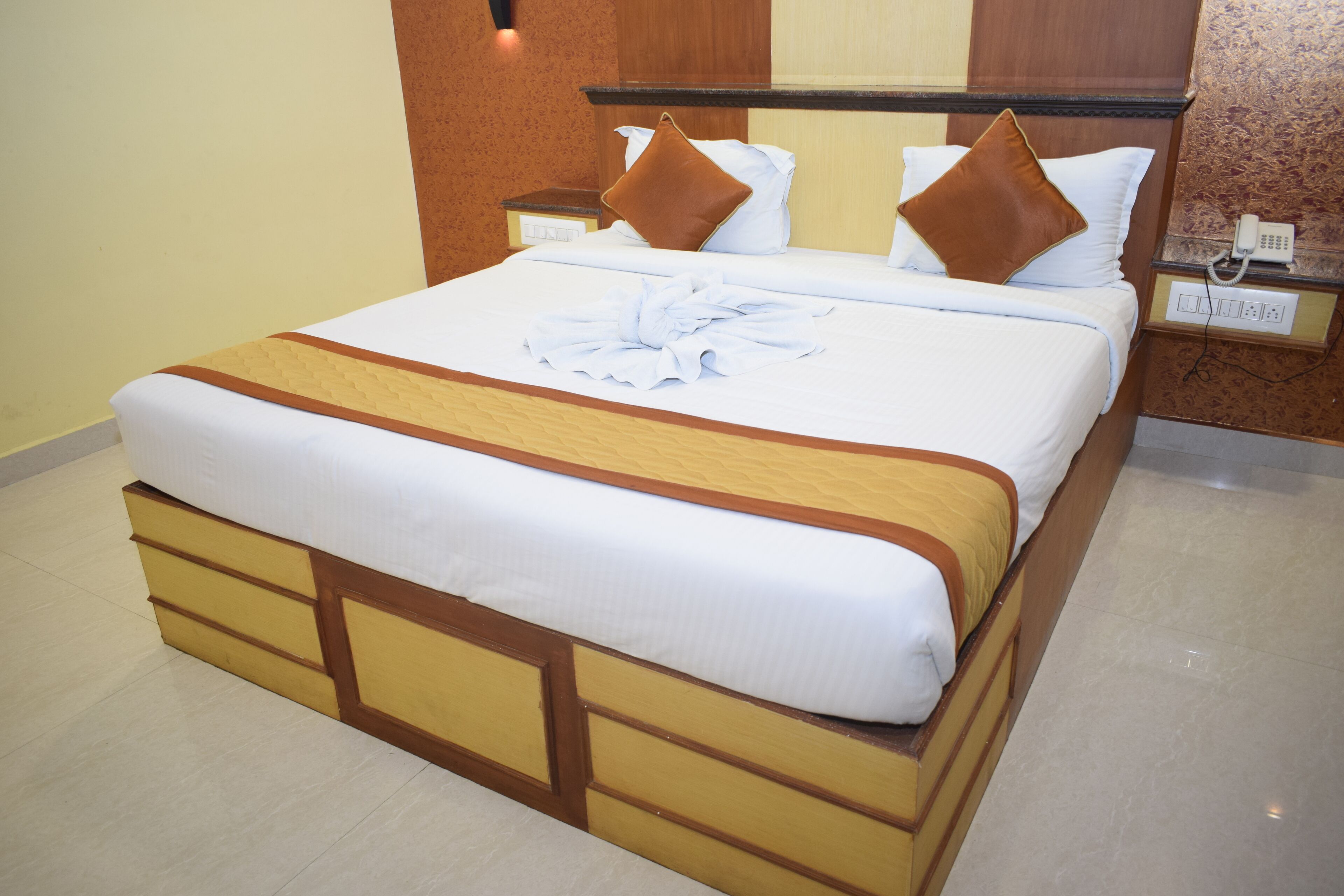 A neatly made bed with a brown headboard, white bedding, and a brown pillow.