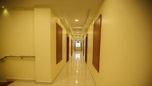 A long, well-lit hallway with wooden doors on both sides, leading to a bright room at the end. - I Residency (Puducherry)