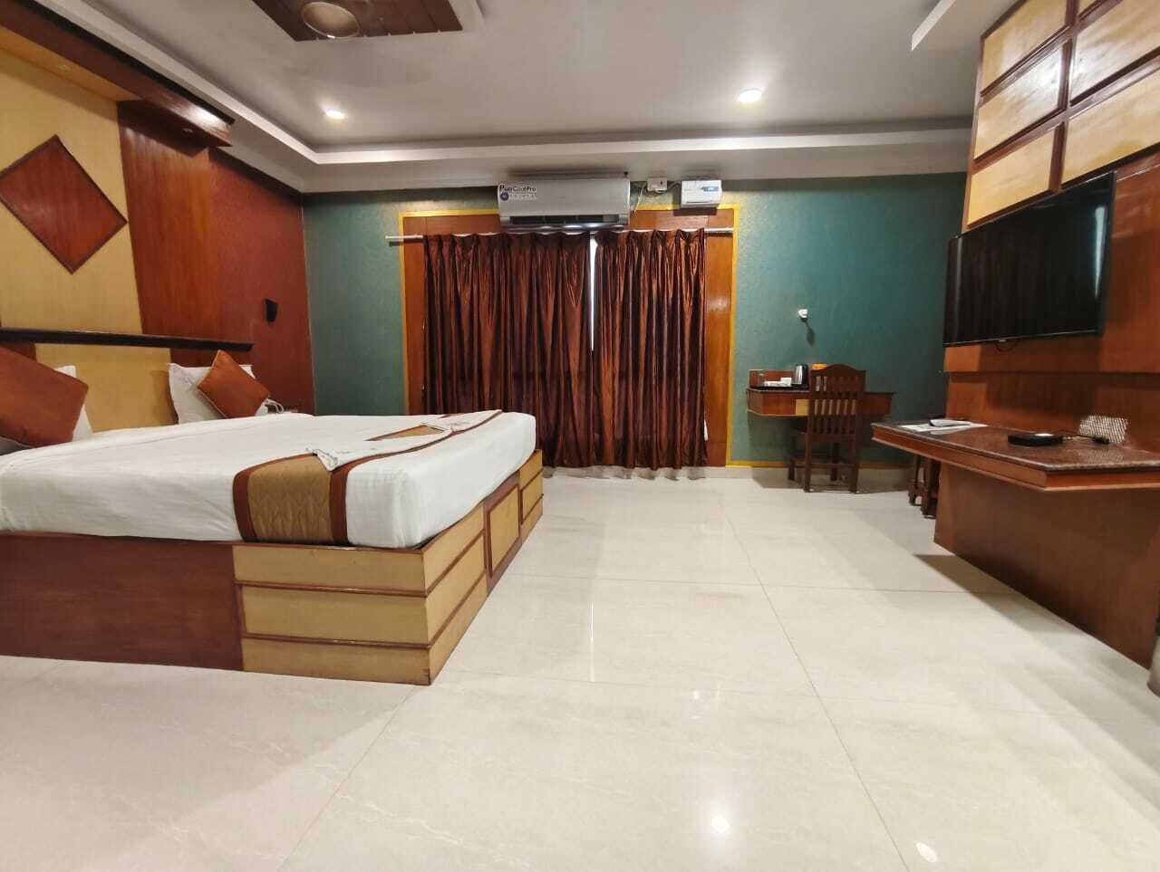 Une chambre d’hôtel avec un grand lit, un bureau, une chaise et un téléviseur.