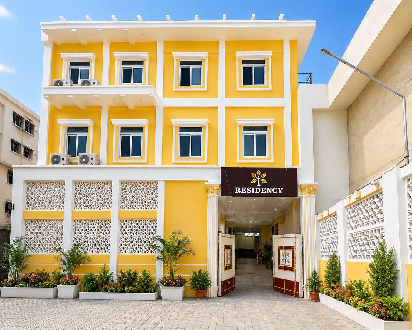 A multi-story building with a yellow facade, a central entrance with a decorative gate, and a sign reading 'RESIDENCY'.