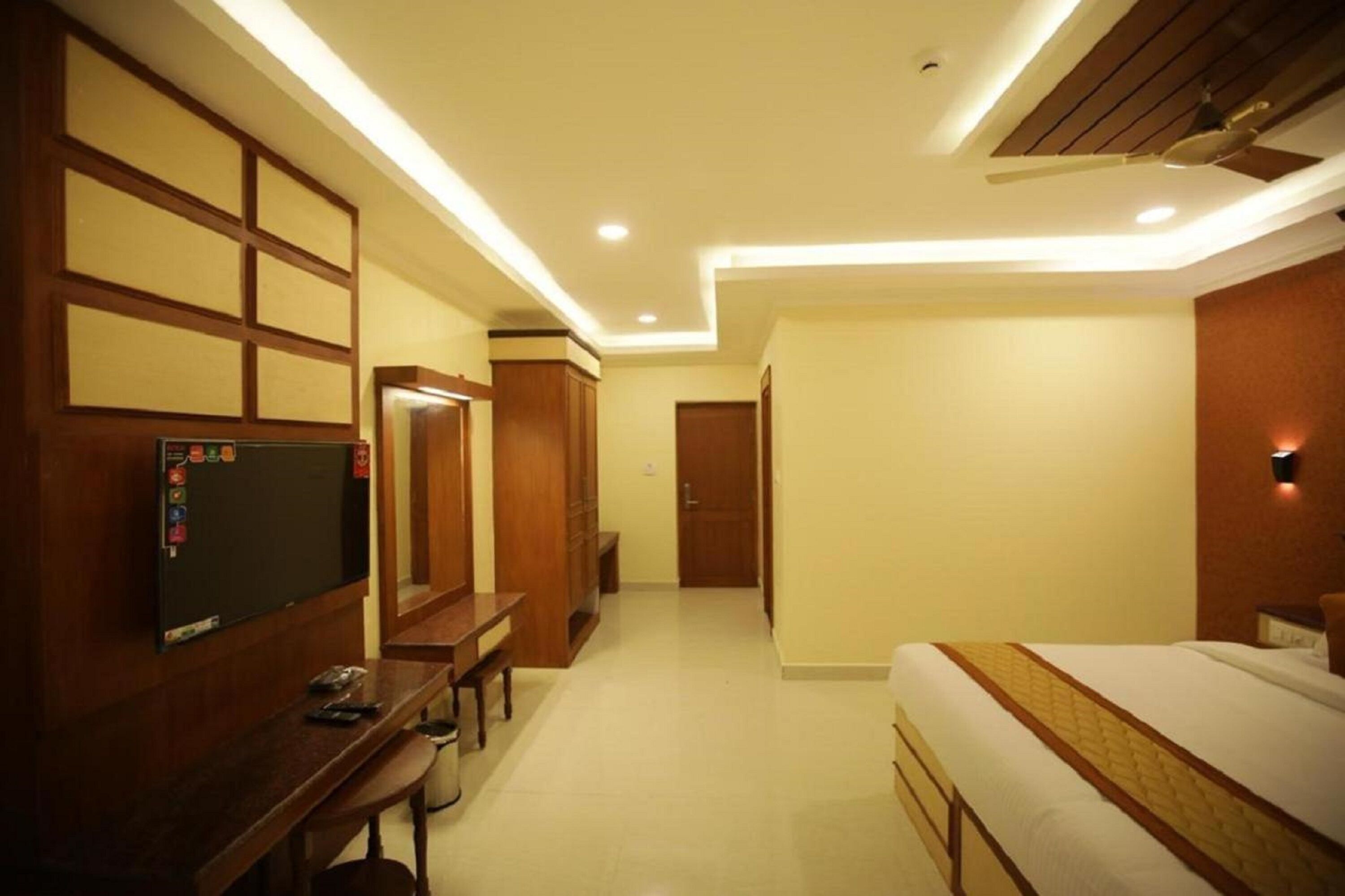 A hotel room with a bed, a desk, a television, and a wardrobe.