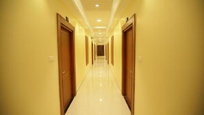 A long, well-lit hallway with wooden doors on both sides, leading to multiple rooms. - I Residency (Puducherry)