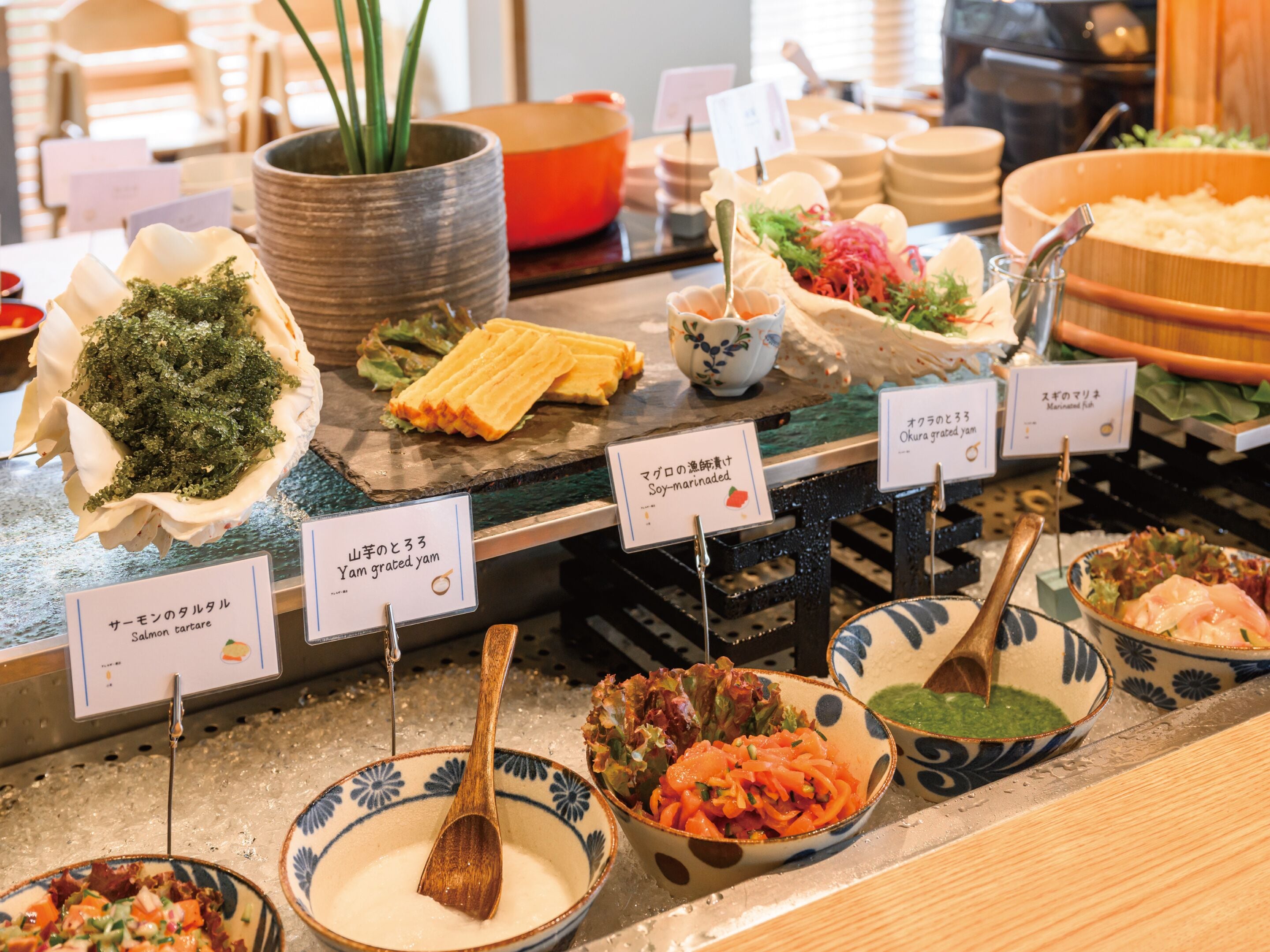 A buffet with various dishes including salmon tartare, soy-marinated salmon, and okura grated yam.