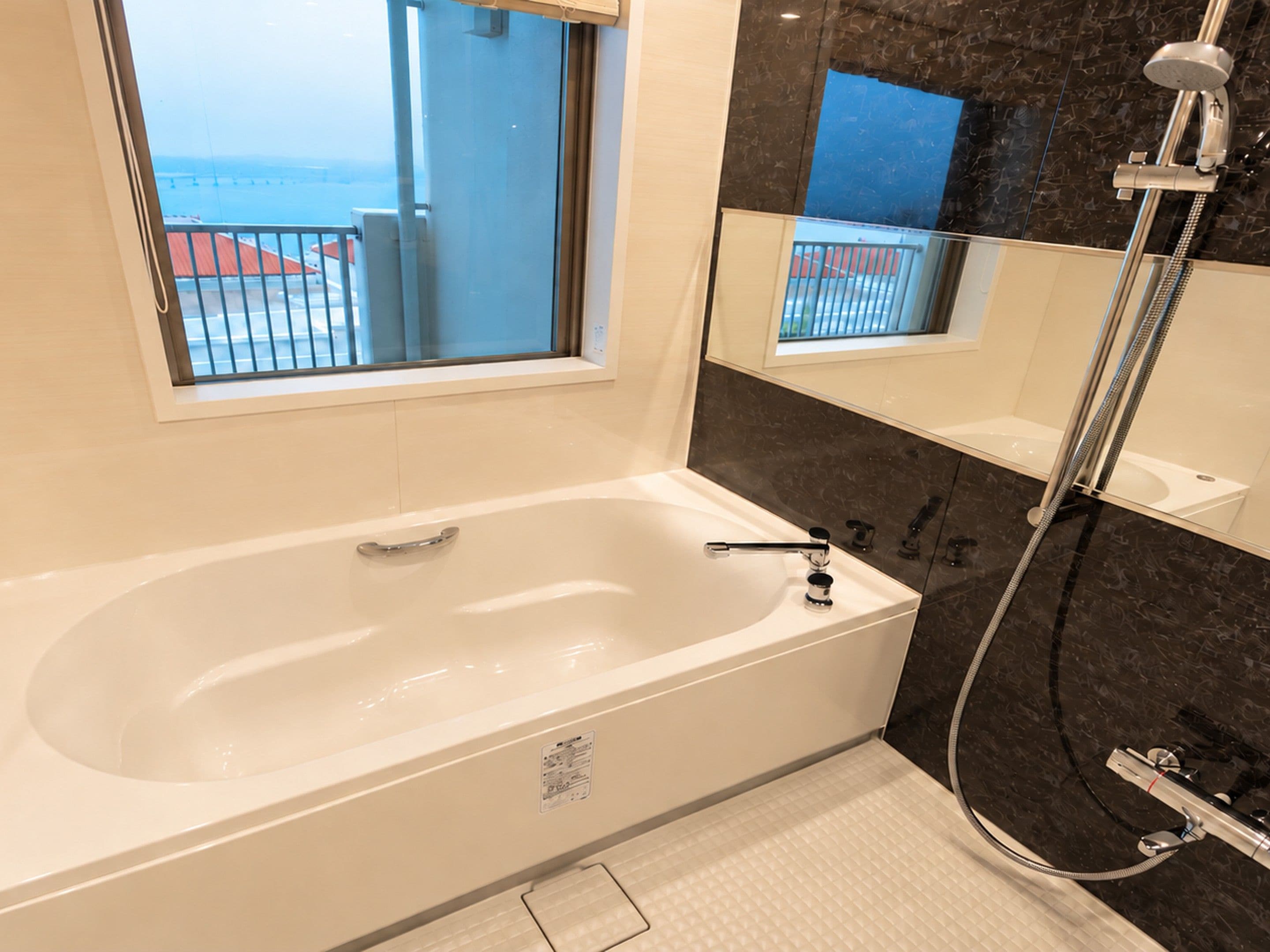 Un baño moderno con bañera, ducha y un amplio ventanal con vistas al mar.