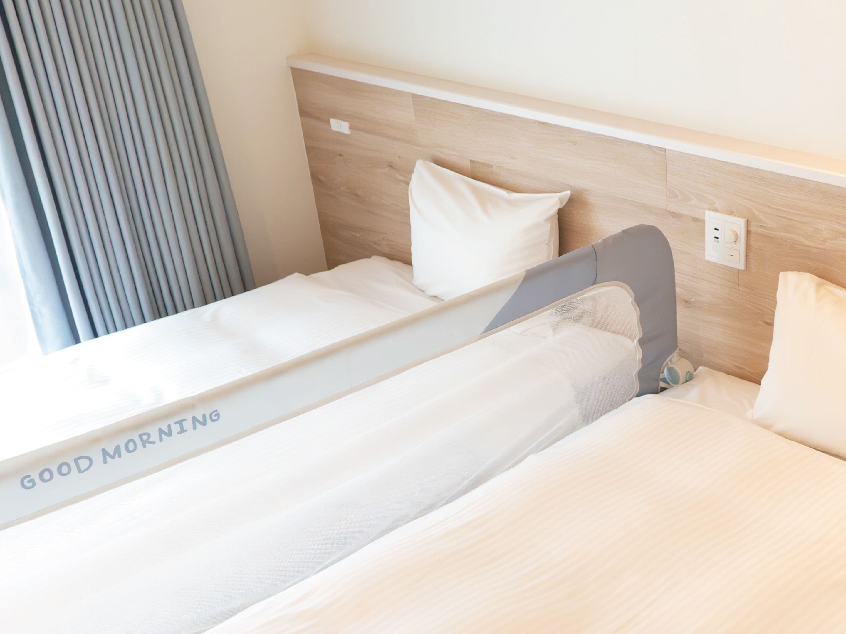 Una cama individual con cabecera, un almohadón y una mesita de noche con lámpara.