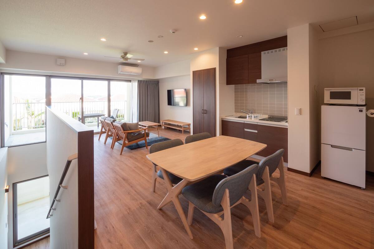 A modern apartment with a dining area, kitchen, and a balcony with a view.