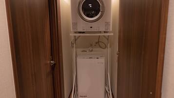 A compact laundry room with a front-loading washer and dryer, a small sink, and a circular window above the dryer.