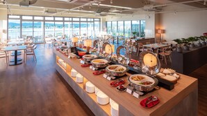 Ein reichhaltiges Buffet mit verschiedenen Speisen und eine Sitzgelegenheit mit Tischen und Stühlen.