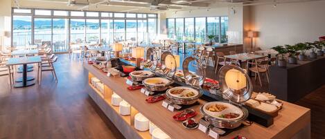 A buffet setup with various food items and a seating area with tables and chairs.