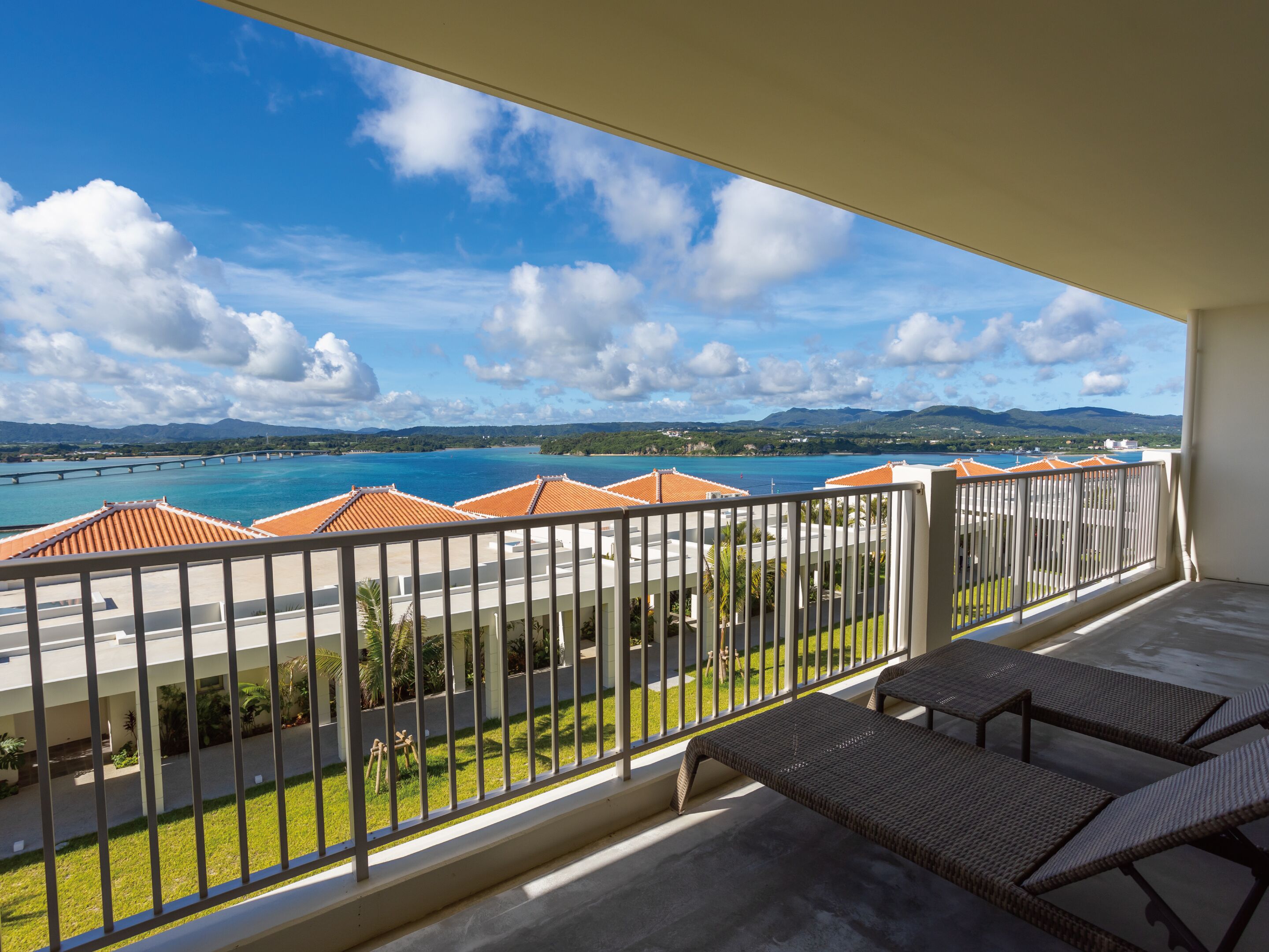 A balcony with a view of a beach and mountains.