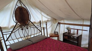 A tent with a bed, a small table, and a nightstand.