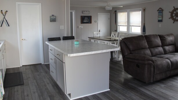 A spacious living area with a large island, a brown leather sofa, and a dining table with chairs. - Updated & short walk to downtown Charlevoix! (Charlevoix)