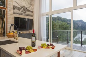 Enjoy a meal with a view from this kitchen, featuring a large island with a selection of gourmet foods and a TV for entertainment.