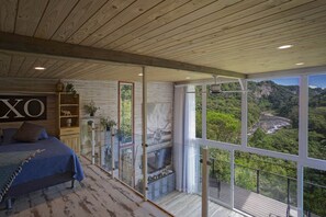 Relax in this serene bedroom with a large bed and scenic views of the lush landscape.