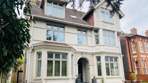 A two-story house with a bay window, a front door with a small porch, and a brick wall. - Luxury Apartment-Golden Triangle, Parking & Garden (Norwich)