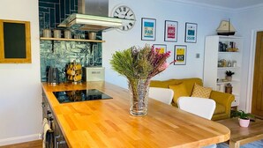 A modern kitchen with a wooden countertop, a vase of flowers, a clock, and a bookshelf. - Luxury Apartment-Golden Triangle, Parking & Garden (Norwich)