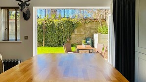 A dining area with a large wooden table, a mounted deer head on the wall, and a view of a garden through a glass door. - Luxury Apartment-Golden Triangle, Parking & Garden (Norwich)