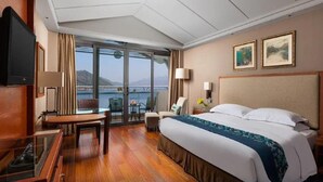 Habitación de hotel con una cama grande, televisión, escritorio y balcón con vistas al mar.