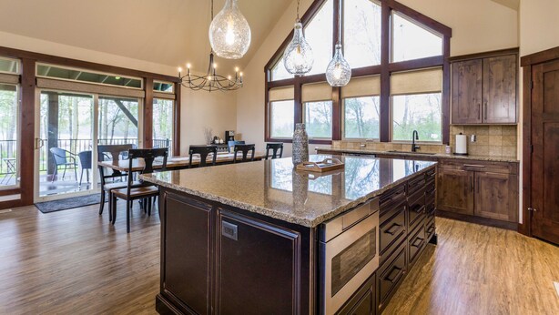 Una cocina amplia con una isla grande, armarios de madera y un comedor con sillas y una mesa.
