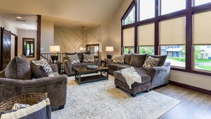Amplia sala de estar con ventanas grandes, chimenea y un rincón de descanso acogedor con sofás y una mesa de centro.