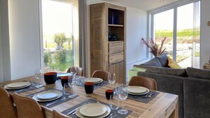 Comedor con una mesa de madera dispuesta para seis personas, rodeado de sillas y vistas a zonas verdes.
