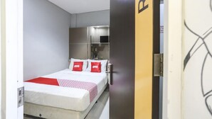 Een hotelkamer met een bed, een kitchenette en een deur met een logo.