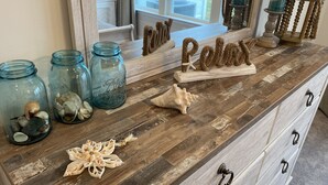 A wooden dresser with drawers, a mirror, and decorative items including seashells and a rope starfish. - Brand New Luxury Property at The Peninsula- Double Master Sleeps 10 (Millsboro)
