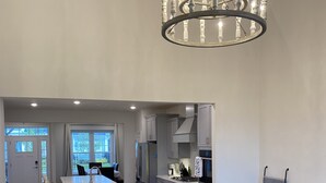 A spacious living room with a black leather sectional sofa, a wooden coffee table, and a chandelier. - Brand New Luxury Property at The Peninsula- Double Master Sleeps 10 (Millsboro)