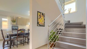 A modern kitchen with a dining area, a staircase, and a potted plant. - Villa Zara by Interhome (Pula)