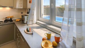 A modern kitchen with a large window, a stove, and various kitchen items on the counter. - Villa Zara by Interhome (Pula)