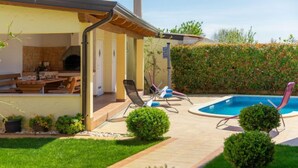 A modern outdoor patio with a pool, lounge chairs, and a barbecue area. - Villa Zara by Interhome (Pula)