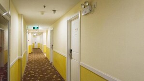 A hotel hallway with yellow and white walls, patterned carpet, and doors leading to rooms. - Home Inn Beijing Communication University of China West Gate (Beijing)