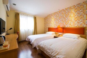 Habitación de hotel con dos camas, un escritorio con ordenador y una pared con estampado de lunares.