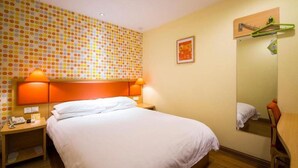 A hotel room with a bed, nightstands, a mirror, and a wall with a polka dot pattern. - Home Inn Beijing Communication University of China West Gate (Beijing)
