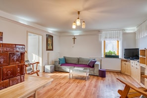 A living room with a sofa, a coffee table, a wooden bench, a television, and a window with blinds. - Farmhouse Blackberry Pool&Wellness, Vransko, Slovenia (Vransko)